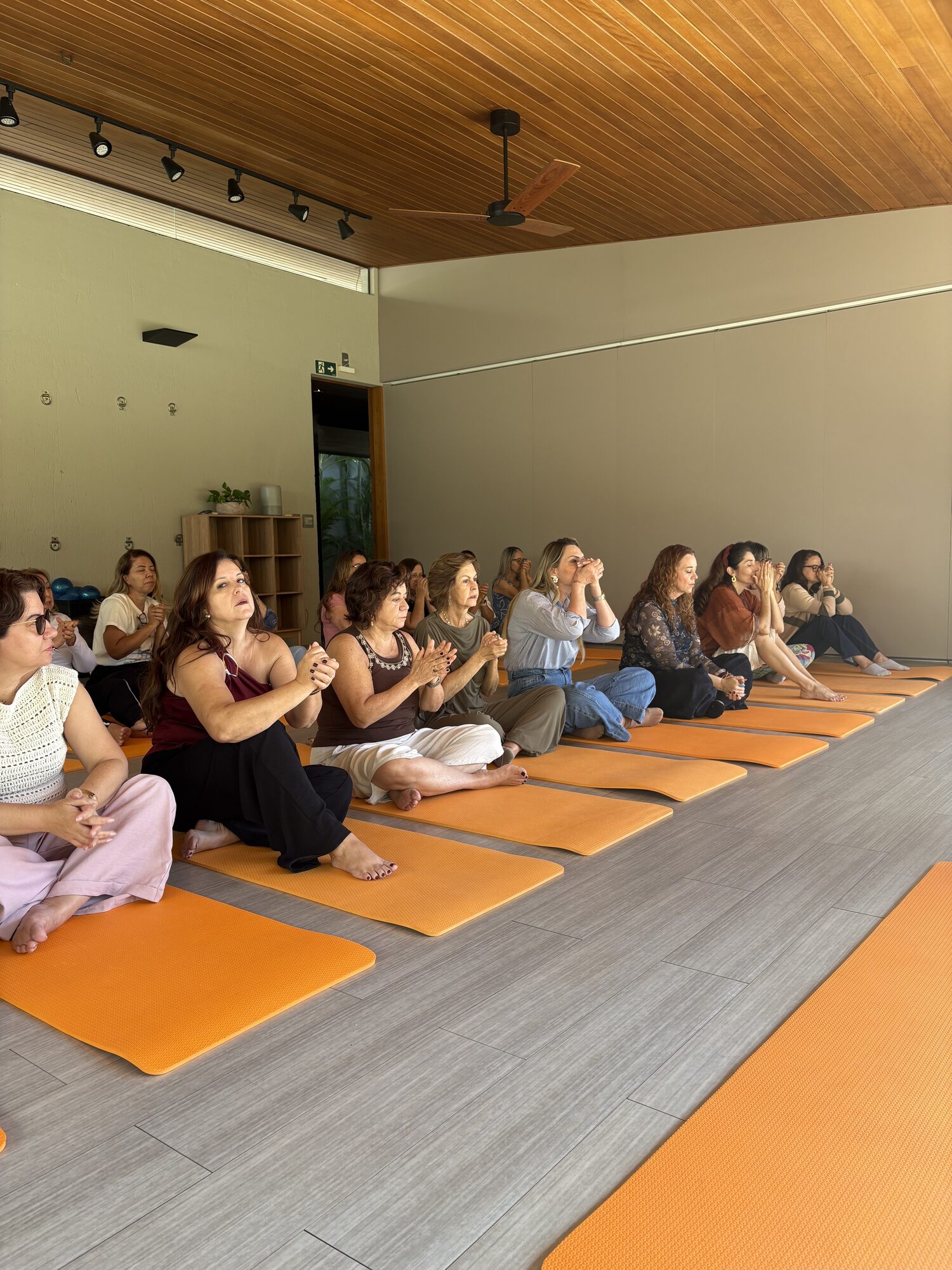 Círculo de mulheres sentadas em tapetes laranjas no momento de abertura da Casa Aromamundo