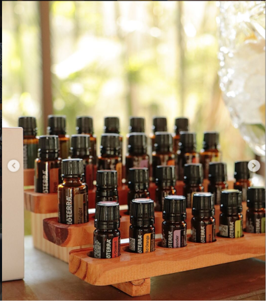 Coleção de óleos essenciais doTERRA em suporte de madeira, com luz natural