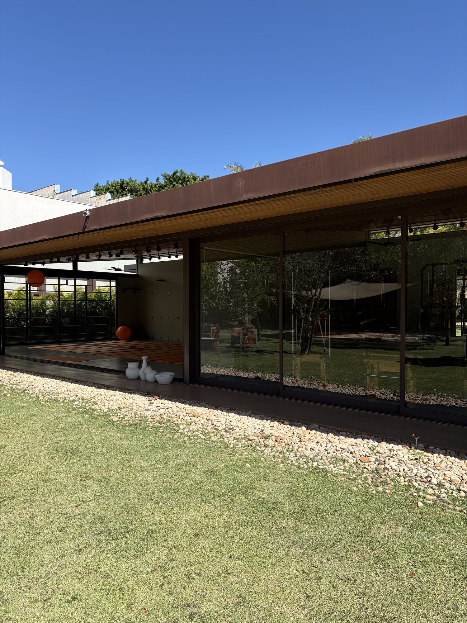 Fachada de vidro e madeira da Casa Aromamundo com o estúdio de yoga visível ao fundo