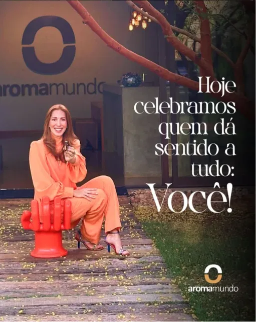 Fundadora da Aromamundo, sentada em frente ao símbolo da marca